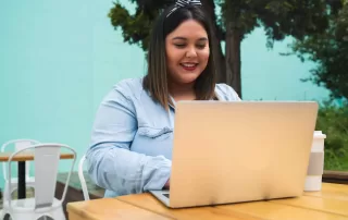 a woman sitting on a wooden table with a laptop