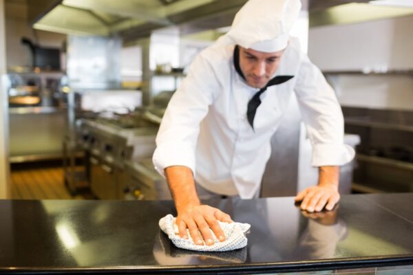 A chef wiping the counter top in the kitchen