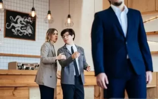 two people talking behind someone in a suit