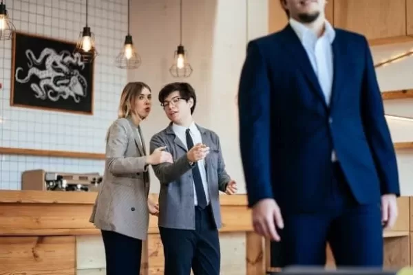 two people talking behind someone in a suit